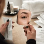 Maquillage yeux semi permanent, ras de cil discret en gros plan sur praticienne et miroir